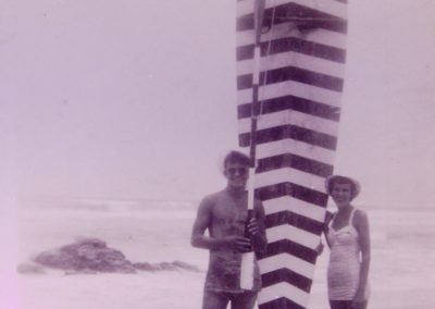 man and woman next to large striped surfboard 1950s point lookout surf life saving club
